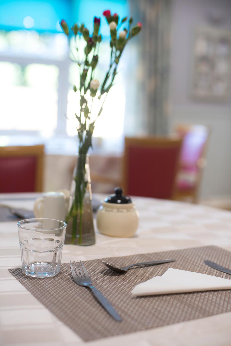 cutlery and vase with flowers on a dining table