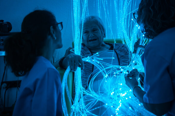 resident playing with optic lights with staff in sensory room