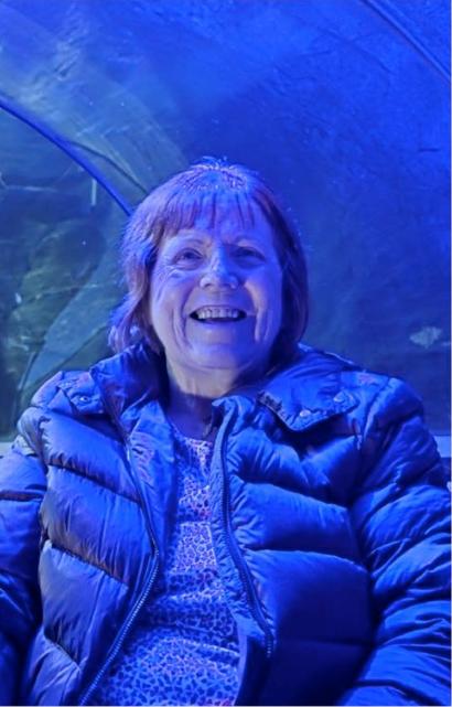 elderly woman smiling in the blue light of an aquarium